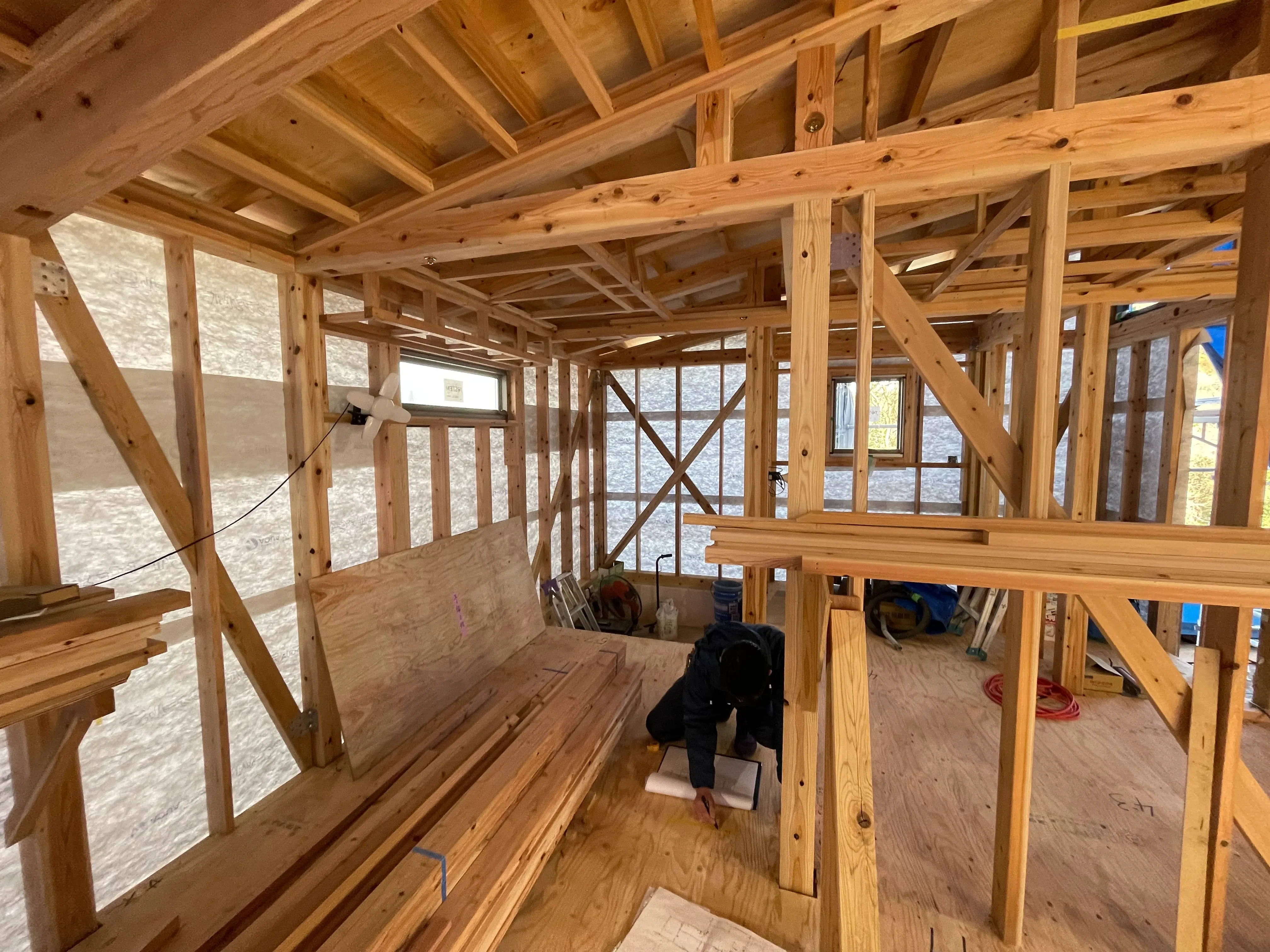 木造建築の現場で図面を確認する大工